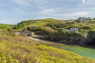 a house on top of a hill next to a river at No2 The Fish Cellars in Port Isaac