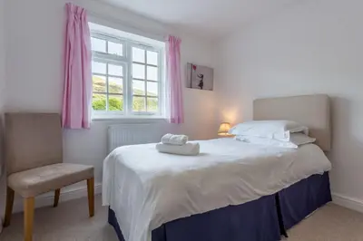 a bedroom with a bed with a chair and a window at No2 The Fish Cellars in Port Isaac