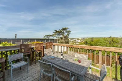 a wooden deck with a wooden table and chairs at Palm Trees in Polzeath
