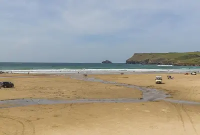 a beach with a few cars parked on the sand at Palm Trees in Polzeath