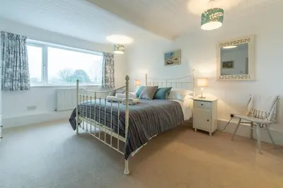a bedroom with a bed and a chair and a window at Palm Trees in Polzeath