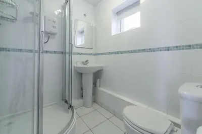 a white bathroom with a toilet and a sink at Palm Trees in Polzeath