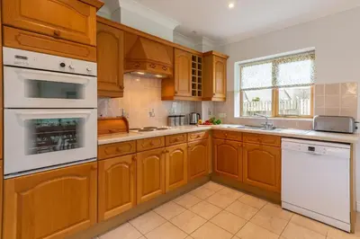 a kitchen with wooden cabinets and white appliances at September Cottage in Wadebridge
