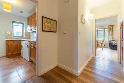 a kitchen with white walls and wooden floors at September Cottage in Wadebridge