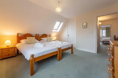 a bedroom with a bed with white sheets and a window at September Cottage in Wadebridge