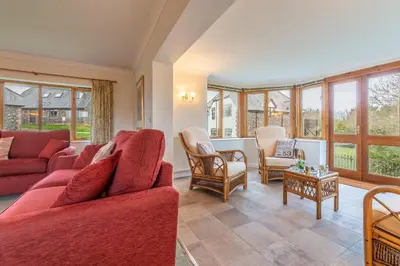 a living room with red furniture and windows at September Cottage in Wadebridge