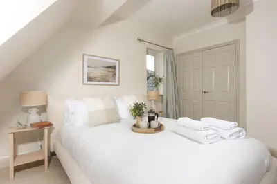 a bedroom with a white bed with towels on it at The Nineteenth in Wadebridge