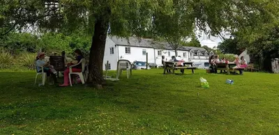 a group of people sitting under a tree in a park at No 4 Trelawney Apartment - Onsite Bar - Restaurant - Horse Riding in Menheniot