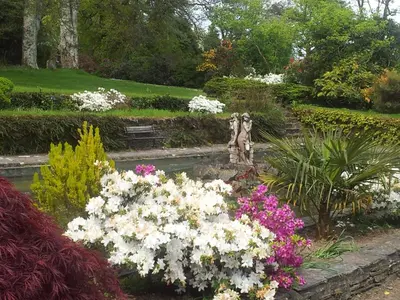 a garden with white and pink flowers and a fountain at No 4 Trelawney Apartment - Onsite Bar - Restaurant - Horse Riding in Menheniot