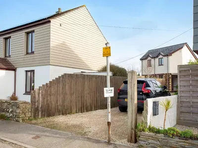 a house with a fence and a car parked in a driveway at Candles Cottage in Cubert