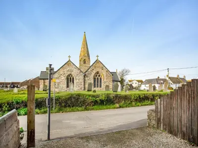 an old stone church with a steeple on a street at Candles Cottage in Cubert