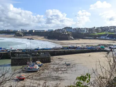 a beach with boats in the sand and a beach with buildings at Candles Cottage in Cubert