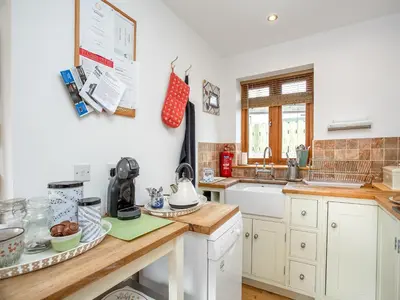 a kitchen with white cabinets and a counter top at Candles Cottage in Cubert