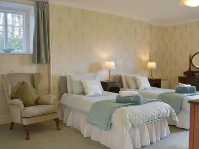 a bedroom with two beds and a chair at Tristan's - Ukc3906 in Lostwithiel