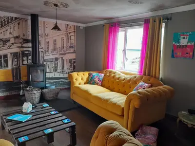 a living room with a yellow couch and a window at Sailaway in Carbis Bay