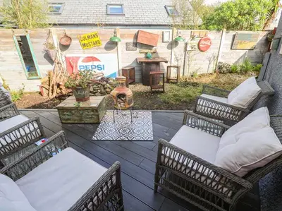 an outdoor patio with three wicker chairs and a table at Sailaway in Carbis Bay