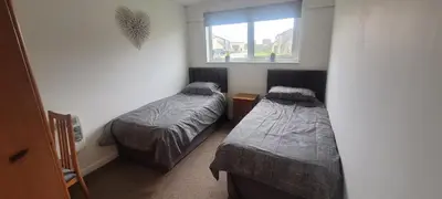 a bedroom with two beds and a window at Perran View Holiday Park in St. Agnes
