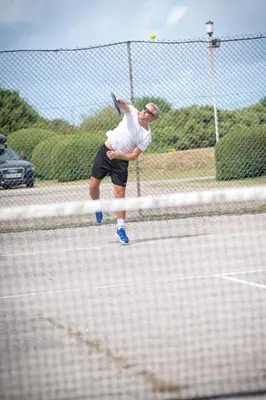 a man hitting a tennis ball on a tennis court at Perran View Holiday Park in St. Agnes