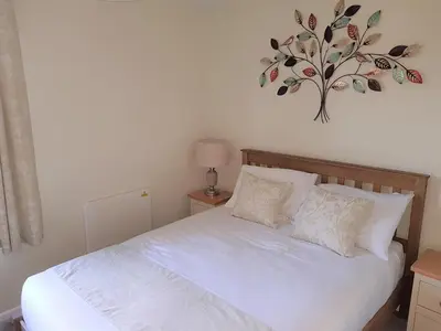 a bedroom with a white bed with a tree on the wall at Perran View Holiday Park in St. Agnes