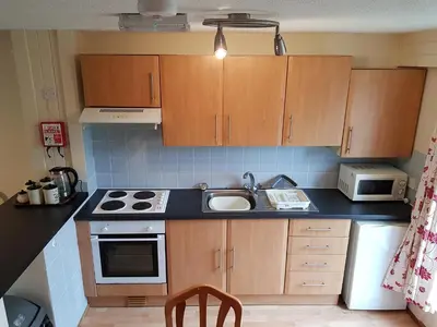 a small kitchen with wooden cabinets and a sink at Perran View Holiday Park in St. Agnes