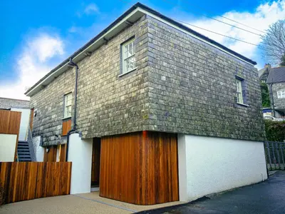 a brick house with wooden doors and a fence at Padstow Escapes - The Long Room Luxury Apartment in Padstow