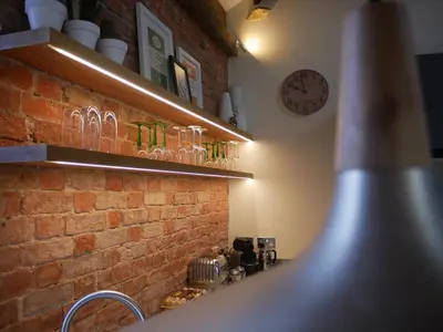a brick wall with shelves and a clock on the wall at Padstow Escapes - The Long Room Luxury Apartment in Padstow