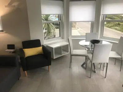 a living room with a table and chairs and windows at Beachy in Newquay