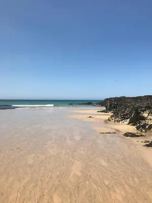 a beach with sand and the ocean with waves at Beachy in Newquay