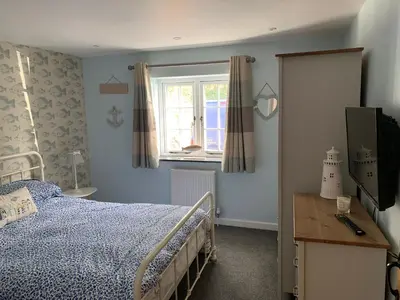 a bedroom with a bed and a window at Bossiney Cove Cottage in Tintagel