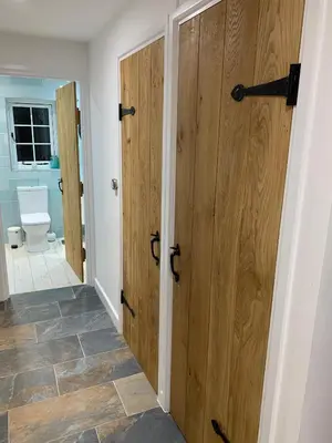 a hallway with two wooden doors and a toilet at Bossiney Cove Cottage in Tintagel
