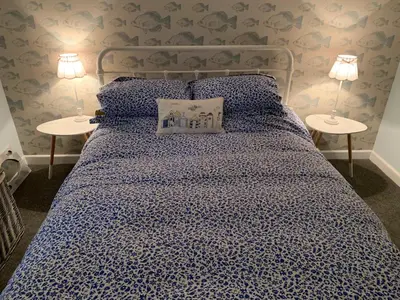 a bedroom with a blue bed with two tables at Bossiney Cove Cottage in Tintagel