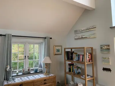 a room with a book shelf and a window at Bossiney Cove Cottage in Tintagel