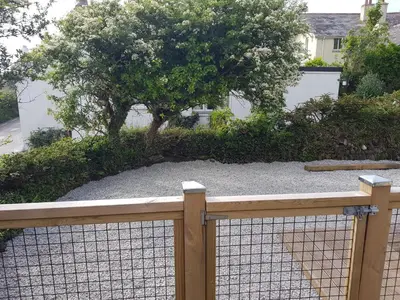 a fence in front of a yard with a tree at Bossiney Cove Cottage in Tintagel