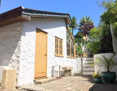a small white house with a wooden door at Quay Courtyard, on the harbour with free parking in Charlestown