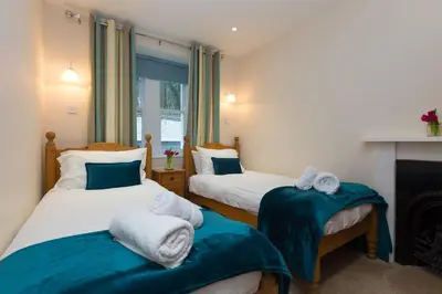 two beds in a room with a fireplace at Coastguard House in St Ives