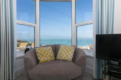a couch with two pillows sitting in front of a window at Sea Crest in St Ives