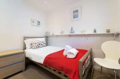 a small bedroom with a bed and a table at Number One - Stones Court in St Ives