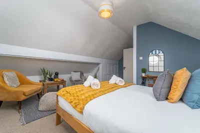 a bedroom with a large bed and a chair at Number One - Stones Court in St Ives