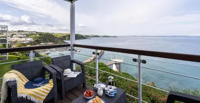 a balcony with a view of a body of water at Marine Point, Mevagissey - sensational cliff top views of harbour and bay in Mevagissey