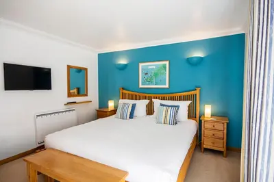 a bedroom with a large bed with a blue wall at Marine Point, Mevagissey - sensational cliff top views of harbour and bay in Mevagissey