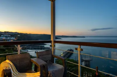 a balcony with two chairs and a view of the ocean at Marine Point, Mevagissey - sensational cliff top views of harbour and bay in Mevagissey