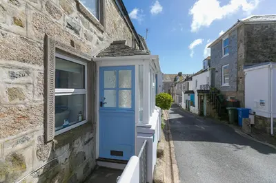 a brick building with a blue door on a street at 85 Back Road East in St Ives
