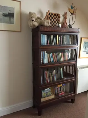 a book shelf full of books with a teddy bear on top at QUILLET COTTAGE, 2 GLENTOWAN ROAD in St Austell