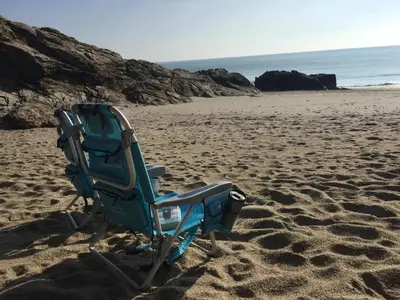 a beach chair sitting on the sand on a beach at QUILLET COTTAGE, 2 GLENTOWAN ROAD in St Austell