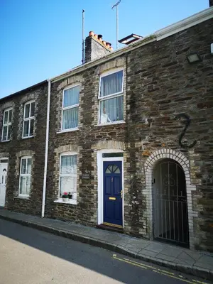 a brick building with a blue door on a street at QUILLET COTTAGE, 2 GLENTOWAN ROAD in St Austell