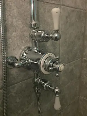 a shower with chrome piping in a bathroom at QUILLET COTTAGE, 2 GLENTOWAN ROAD in St Austell