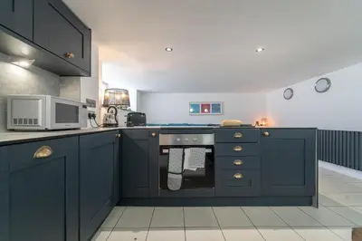 a kitchen with blue cabinets and a microwave at Mariner's Belle in St Ives