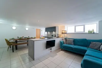 a living room with a blue couch and a kitchen at Mariner's Belle in St Ives