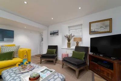 a living room with a yellow couch and a flat screen tv at Shrimp Cottage in St Ives