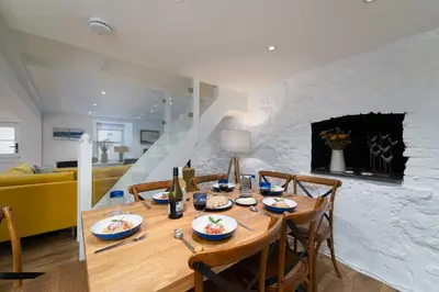 a dining room with a table and chairs and a fireplace at Shrimp Cottage in St Ives